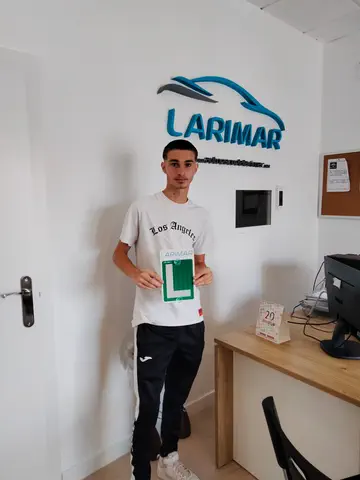 Foto de un aprobado: placa L en mano en la oficina de Autoescuela Larimar