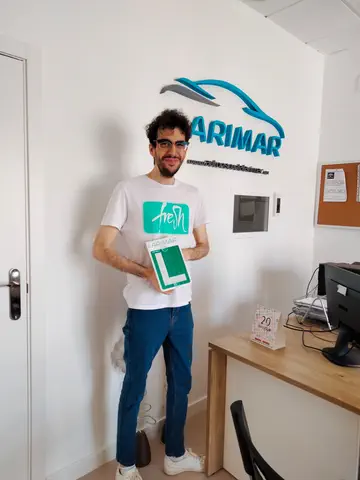 Foto de un aprobado: placa L en mano en la oficina de Autoescuela Larimar