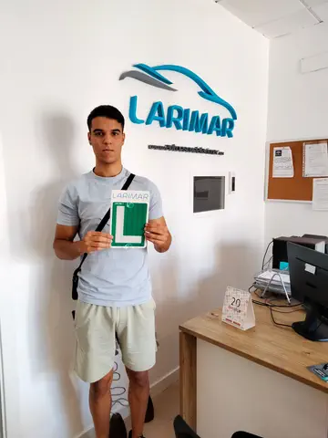 Foto de un aprobado: placa L en mano en la oficina de Autoescuela Larimar