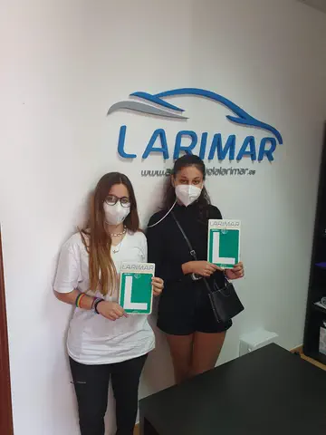 Dos aprobados con sus placas L en la oficina de Autoescuela Larimar