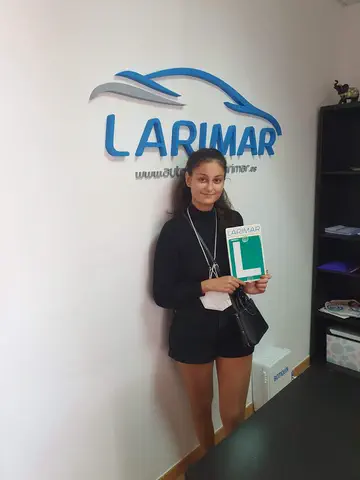 Foto de un aprobado: placa L en mano en la oficina de Autoescuela Larimar