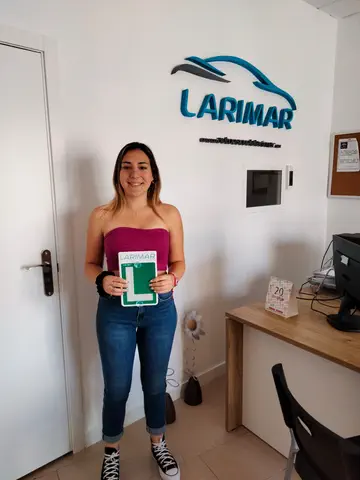 Foto de un aprobado: placa L en mano en la oficina de Autoescuela Larimar