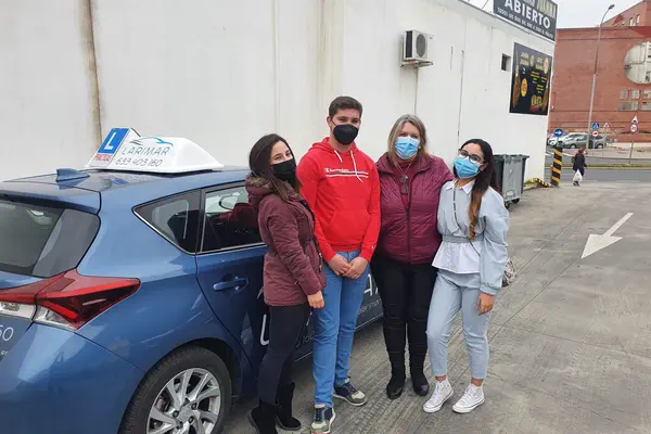 Cuatro personas con la placa L junto al coche de prácticas de Autoescuela Larimar