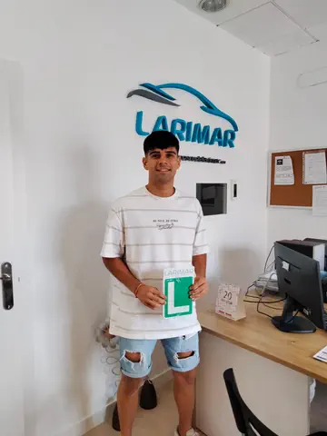 Foto de un aprobado: placa L en mano en la oficina de Autoescuela Larimar