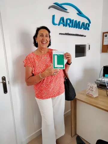 Foto de un aprobado: placa L en mano en la oficina de Autoescuela Larimar