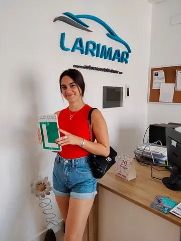 Foto de un aprobado: placa L en mano en la oficina de Autoescuela Larimar