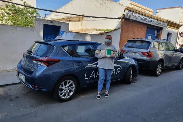 Una persona con la placa L junto al coche de prácticas de Autoescuela Larimar