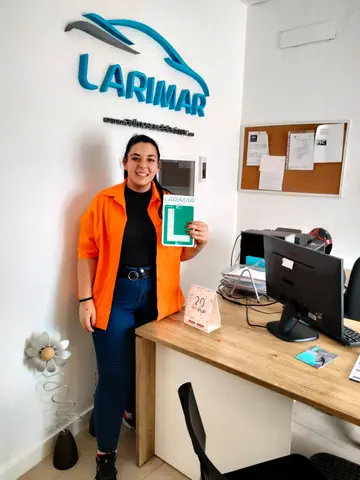Foto de un aprobado: placa L en mano en la oficina de Autoescuela Larimar